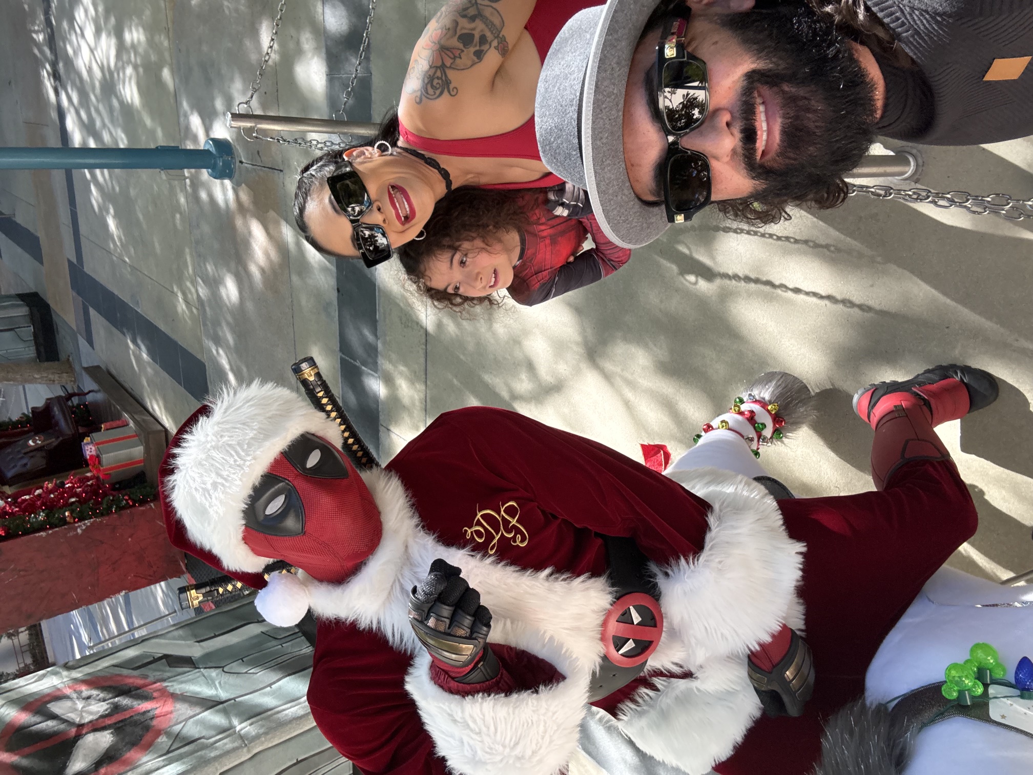 A family taking a selfie with Deadpool in a holiday costume at Avengers Campus