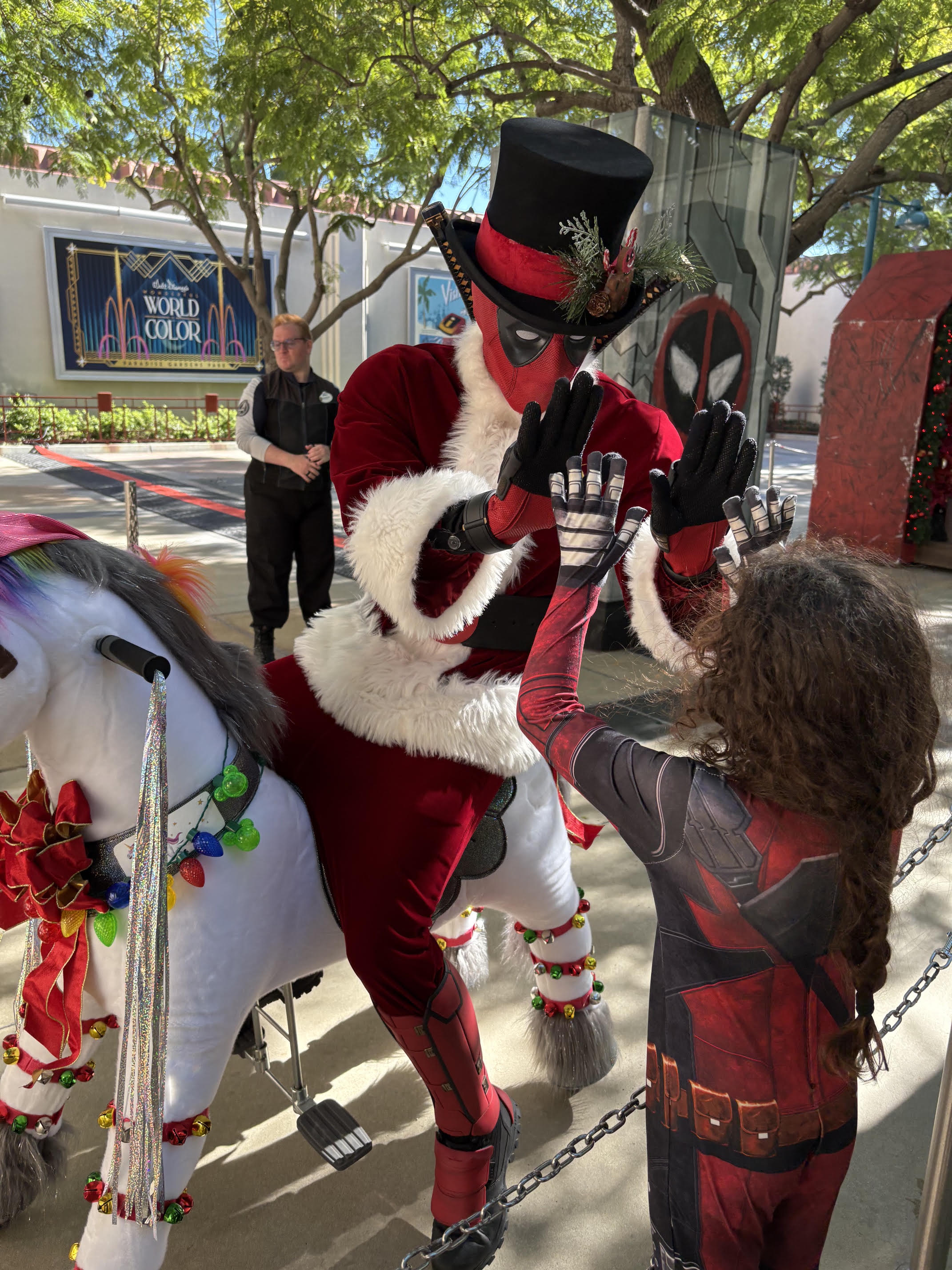 A child dressed as Deadpool high-fiving Deadpool at Avengers Campus